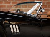 an image of a black sports car parked in front of a brick wall