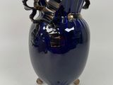 a blue vase with a handle on it on a white surface