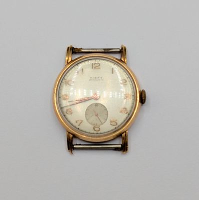 une montre-bracelet en or avec un cadran blanc sur une surface blanche