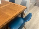 a wooden table with blue chairs and a vase on it