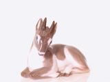 une statue représentant un cerf couché sur une surface blanche