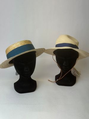deux chapeaux posés sur une tête de mannequin ornée d'un ruban bleu