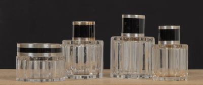 trois bouteilles en verre transparent avec des bouchons noirs, posées sur une table en bois