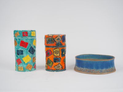 trois vases de couleurs différentes posés les uns à côté des autres sur une surface blanche