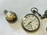 a silver pocket watch and a silver pocket watch on a white table