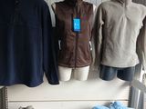 several jackets and sweaters hanging on a rack in a clothing store