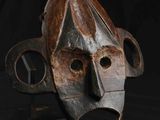 une image d'un masque en bois sur fond noir