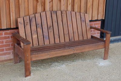 un banc en bois posé devant un mur de briques