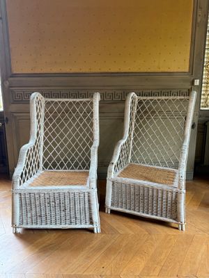 une paire de chaises en osier blanc posées sur un parquet dans un salon