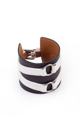 un gros plan sur un bracelet en cuir noir et blanc muni d'un fermoir en métal
