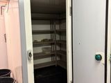 une grande porte ouverte donnant sur une pièce où se trouve une poubelle