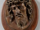 une image représentant une tête de Jésus en bronze sur une plaque en bois