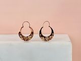 une paire de boucles d'oreilles en anneau en or posée sur un bloc de marbre