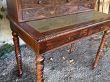 a wooden desk with a leather top on a gravel ground