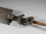 un objet métallique muni d'un manche en bois posé sur une surface blanche