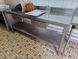 une table en acier inoxydable dans une cuisine, sur laquelle est posé un ordinateur portable