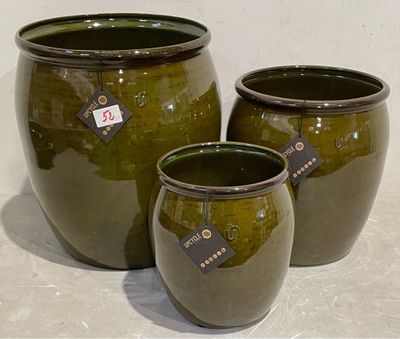 trois vases verts posés les uns à côté des autres sur une table