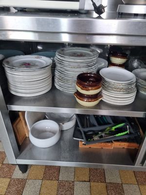 many plates and pans on the shelf in the kitchen