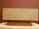 a stone plaque on a wooden stand with carvings on it