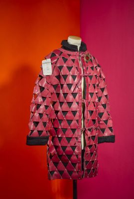 pink and black jacket on a mannequin stand against a red wall