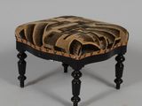 un petit tabouret noir orné d'un motif marron et noir