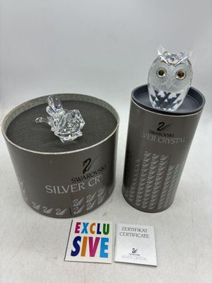 une figurine de chouette en argent dans une boîte en fer-blanc, à côté d'un coffret en argent