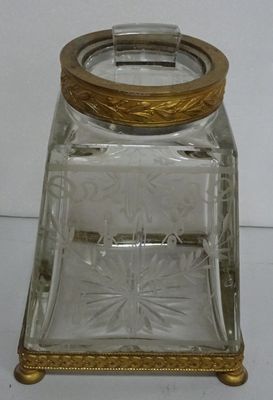 un bocal en verre avec un couvercle doré posé sur une table