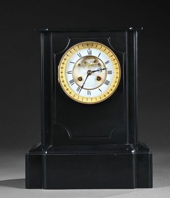 une horloge noire avec un cadran doré, posée sur un socle