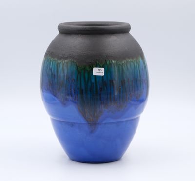 un vase bleu et noir posé sur une surface blanche