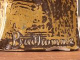 a close up of a brown and yellow vase on a table
