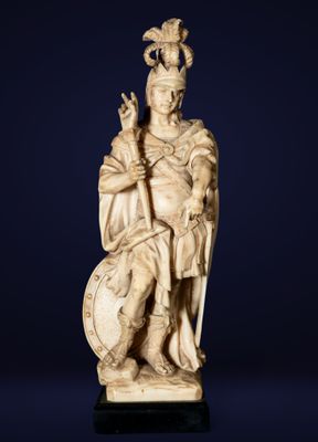 une figurine en ivoire sculpté représentant un homme assis tenant un bouclier et un bouclier