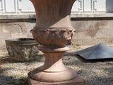 un grand vase en pierre posé sur le gravier devant une maison