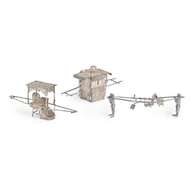trois figurines en métal argenté représentant des personnages et un petit bâtiment