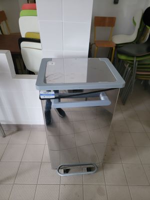 une poubelle argentée posée par terre dans la cuisine