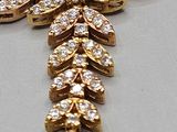 an image of a gold and diamond necklace on a white surface