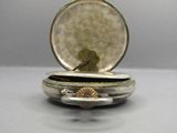 a close up of a pocket watch with a shell in it