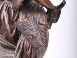 bronze statue of a woman sitting on a rock with a basket