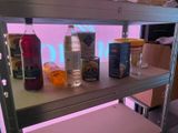 a shelf with bottles of drinks and oranges on it