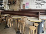 many stools and tables in a room with bottles of wine on the wall