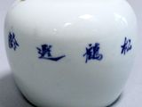 a white vase with blue writing on it sitting on a table