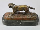 bronze statue of a dog on a marble base on a white surface