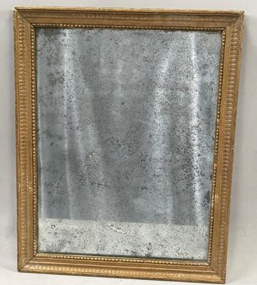 a gold framed mirror sitting on top of a white wall