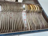 a lot of silver spoons in a box on a table