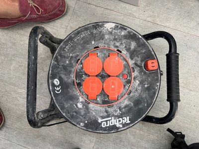 un objet orange et noir posé par terre, près des pieds d'une personne
