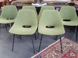 four green chairs sitting in a room with a rug on the floor