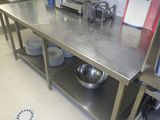 une grande table en acier inoxydable sur laquelle est posé un saladier
