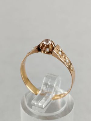 a close up of a gold ring with a diamond on top