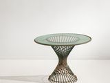 une photo d'une table en verre avec un piètement en métal, posée sur une surface blanche