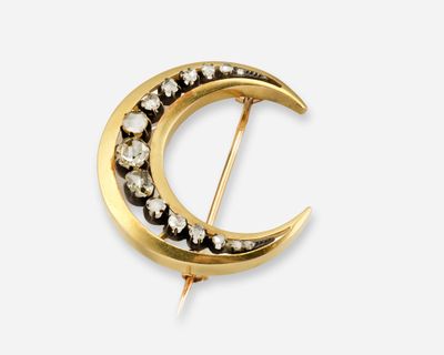 une photo d'une broche en forme de croissant en or, sertie de diamants noirs et blancs