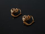 a pair of gold earrings on a black surface